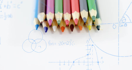 Displaying ten colored pencils lining up on white paper at study desk with blue-ink math sketches....