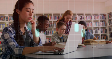 Studying group of students using laptop and notebooks on round library table, with open books, pens. Collaboration, education, learning, teamwork, scholarly, literacy, academicの写真素材