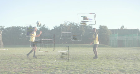 Male soccer player wearing yellow jersey heading soccer ball on grassy field, with digital overlays....