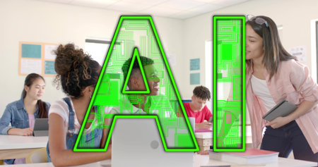 Guiding teacher leaning over student desks in bright classroom, with laptops and tablets. Education,...