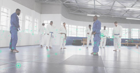 Instructor in blue gi leading group on mats inside training hall, with windows, copy space. Martial...