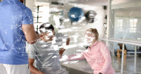 Assisting therapist in light pink top supporting seated client on bench in rehab studio, overlay. Rehabilitation, fitness, mobility, recovery, mirror, windows, equipmentの写真素材