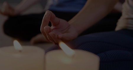Showing woman's hand forming mudra on striped leggings and yoga mat at yoga studio, with candles. Zen, mindfulness, tranquility, wellness, spirituality, meditation, relaxationの写真素材