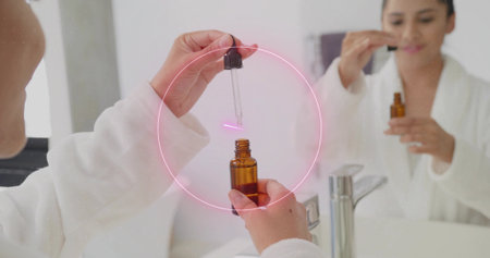 Using dropper pipette woman in white bathrobe transferring serum into amber bottle at bathroom sink....