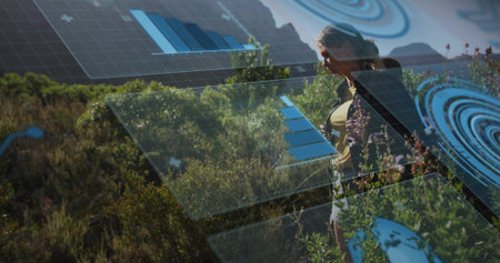 Viewing hiker in athletic wear analyzing digital panels with charts on hillside trail, copy space. Futuristic, technology, outdoor, wellness, analytics, landscape, adventureの写真素材