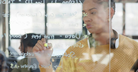 Drawing woman in yellow sweater using yellow marker on glass board in office space, copy space....
