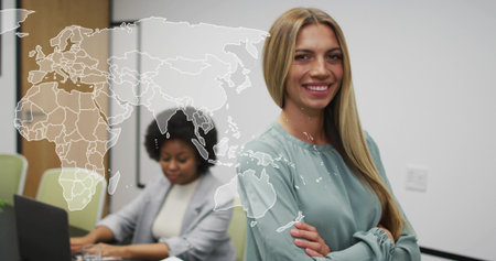 Standing blonde staff member crossing arms in boardroom, with laptop and world map, copy space....