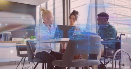 Collaborating wheelchair user and two colleagues using laptop in kitchen with digital overlays. Corporate, teamwork, innovation, modern, inclusive, technology, collaborationの写真素材