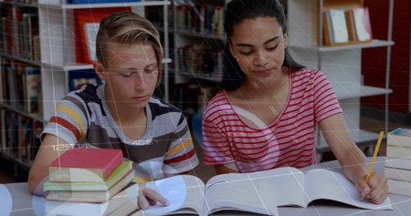 Reading striped-shirt boy and writing red-shirt girl studying at library, with pencil and textbooks. Academic, collaboration, literacy, focus, concentration, education, study environmentの写真素材