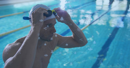 Tightening male swimmer securing goggles at lap pool, white swim cap and yellow lane dividers. Athlete, aquatic, dynamic, competitive, training, sports, performanceの写真素材