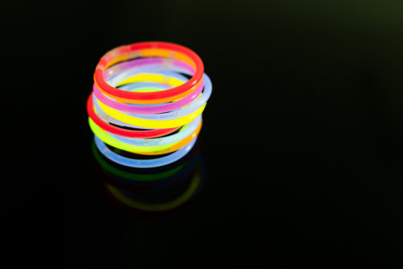Image of vibrant round neon glow sticks stacked over black background with copy space. Light and colour concept.の写真素材