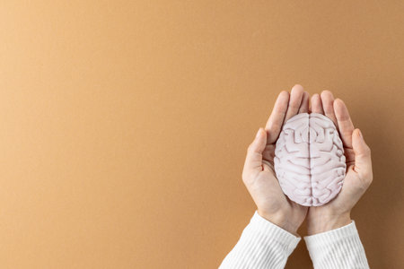 Composition of hands holding brain on brown background with copy space. Medical services, healthcare and mental health awareness concept.の写真素材