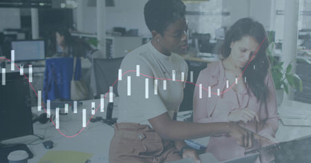 Collaborating office colleagues pointing and tapping tablet at open-plan desk, financial overlay. Collaboration, teamwork, productivity, modern, corporate, communication, innovationの写真素材