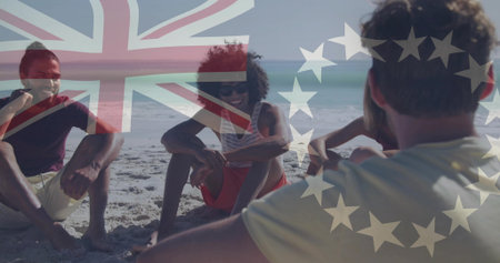 Chatting friends wearing T-shirts and shorts sitting on beach, with Union Jack and stars overlay....