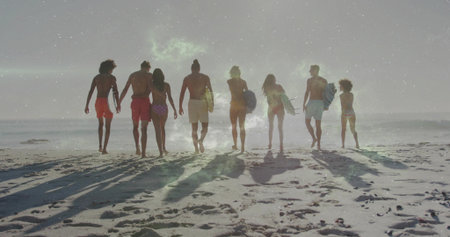 Walking group of eight surfers in swimwear carrying surfboards toward ocean at beach, wet sand....