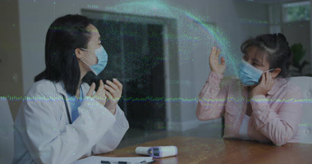 Discussing masked provider and patient gesturing at clinic table, with screen and digital overlay. Medical, telehealth, consultation, digital, healthcare, communication, professionalの写真素材