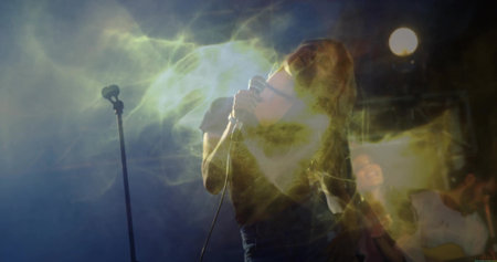 Singing female performer in dark t-shirt and jeans on stage, with wired microphone and haze effects. Performance, concert, acoustic, entertainment, nightlife, atmosphere, dynamicの写真素材