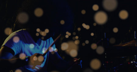 Playing Indian drummer delivering rhythms on venue stage, with drum kit, drumsticks, bokeh orbs. Musician, live performance, stage lighting, atmospheric, minimalistic, artistic, concertの写真素材