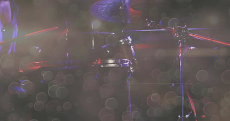 Glinting drum kit catching red spotlights on music venue stage, with haze and microphone stands. Performance, concert, live music, stage, instrumental, acoustic, vibrantの写真素材
