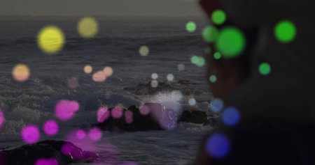 Crashing waves hitting rocks on coast at twilight with bokeh lights, shirted silhouette, copy space....