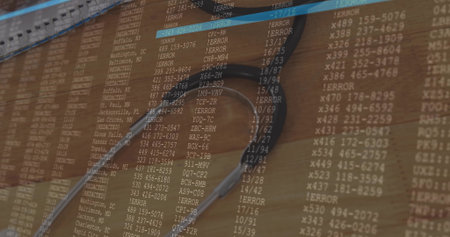 Displaying silver stethoscope resting on wooden desk workspace, featuring computer code overlay....