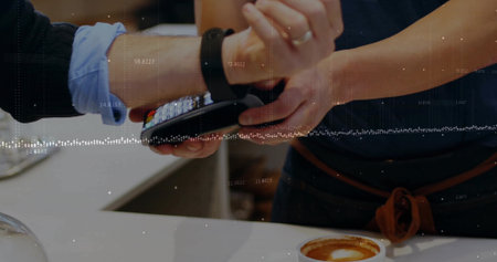 Tapping smartwatch on handheld POS terminal at coffee shop counter, showing latte foam art. Digital...