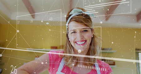 Smiling woman wearing apron and headband standing at kitchen counter, with digital interface data. Cooking, home, modern, lifestyle, interior, cheerful, technologyの写真素材