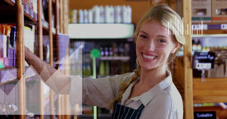 Employee in striped apron arranging packaged goods in aisle, with wooden shelves and digital charts....