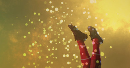 Extending legs wearing red athletic socks and black soccer cleats on golden backdrop, light spots. Athletic, footwear, sport, energy, dynamic, vibrant, motivationの写真素材