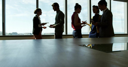 Discussing team exchanging tablets smartphones and notebooks around wooden table in conference room. Collaboration, innovation, teamwork, modern, professional, brainstorming, communicationの写真素材
