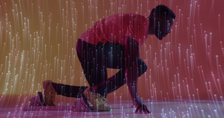 Crouching athlete wearing beige shoes preparing sprint start in studio, with fiber-optic lights. Futuristic, performance, dynamic, innovation, nightlife, vibrant, motionの写真素材