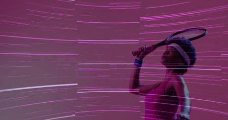 Holding racket overhead, athlete in pink top, white headband, blue wristband in studio, copy space. Athlete, fitness, neon, futuristic, energetic, motivation, sportの写真素材