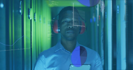 Checking technician wearing red earmuffs with tablet in server aisle, viewing holographic charts. Technology, data, cybersecurity, innovation, digital, network, infrastructureの写真素材