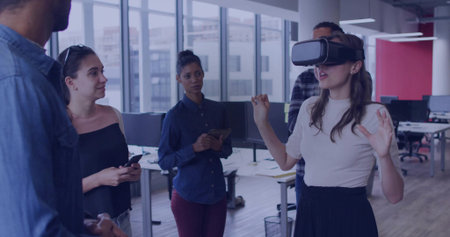 Testing woman interacting with VR headset at modern office, others using mobile devices, copy space....