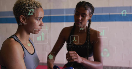 Preparing athletes in sports bras applying hand wraps in boxing gym, with gloves and hologram icons. Athletes, fitness, training, urban, active, motivation, resilienceの写真素材
