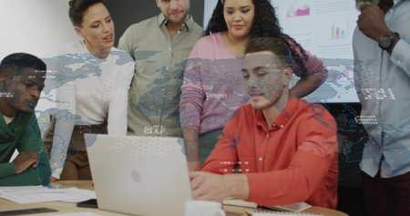 Operating man in red shirt using silver laptop in meeting room at table, with printed charts. Collaboration, teamwork, analytics, innovation, professional, modern, businessの写真素材
