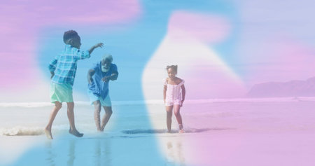 Standing father in swimwear and children splashing in shallow ocean water, with pastel haze overlay. Family, beach, shoreline, recreation, leisure, scenic, pastelの写真素材