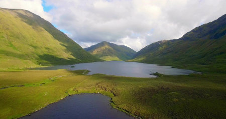 Showcasing central lake reflecting cloud formations in mountain valley, with pond and grassy meadow. Landscape, nature, tranquility, wilderness, scenic, outdoor, reflectionの写真素材