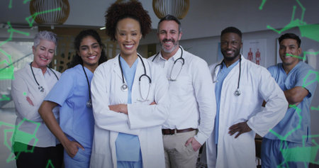 Standing team in clinic hall with scrubs and coats, stethoscopes, charts, lights and green overlays. Medical, collaboration, professionalism, innovation, healthcare, diagnostics, modernの写真素材