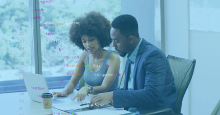 Collaborating colleagues in suits reviewing documents at conference table with laptop and pen. Professional, teamwork, corporate, productivity, modern, business, communicationの写真素材