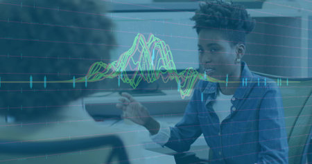 Discussing project office analyst leaning at workstation in modern office, with waveform overlay....