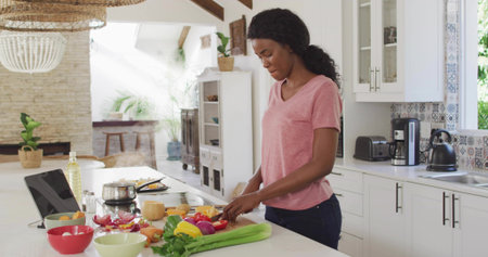 Preparing home cook chopping vegetables on marble island, with cutting board, laptop, copy space. Cuisine, culinary, modern, lifestyle, interior, freshness, healthの写真素材