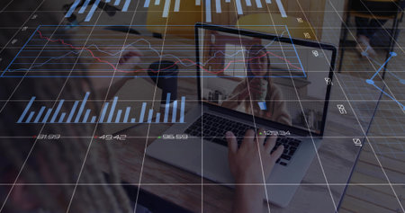 Woman holding coffee mug, typing on laptop at home office table with financial charts during call. Professional, workspace, modern, digital, collaboration, productivity, cozyの写真素材