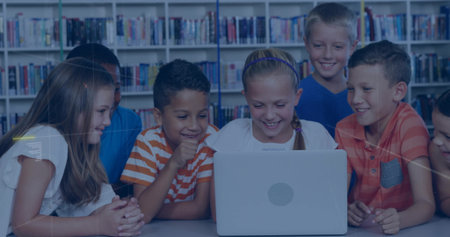 Smiling schoolchildren gathering around laptop in library, with bookshelves backdrop. Collaboration,...