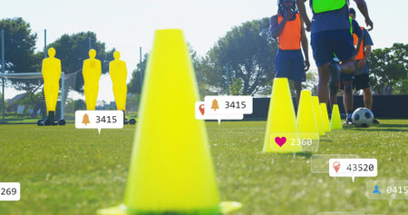 Dominating foreground, bright yellow cone leading drill on grassy pitch, mannequins, bibs, overlays. Soccer, practice, outdoor, field, athletes, goal, conesの写真素材