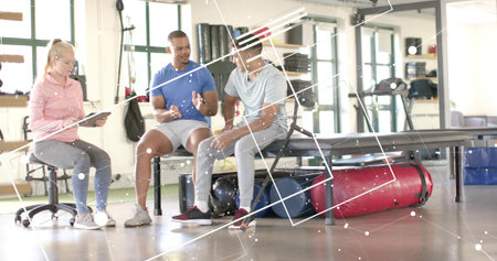 Talking client in blue T-shirt gesturing, trainer in pink holding tablet in rehab studio, equipment....
