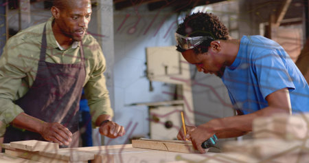 Apprentice carpenter marking plank with pencil tape measure in woodshop, with instructor guiding....