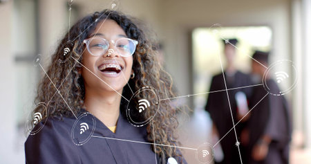Smiling teenage graduate wearing black gown, glasses and braces in campus hall. Adolescence, achievement, communication, education, youthful, successの写真素材