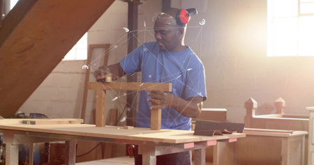 Mature woodworker wearing ear protection handling small wooden frame at workshop bench, with clamps....