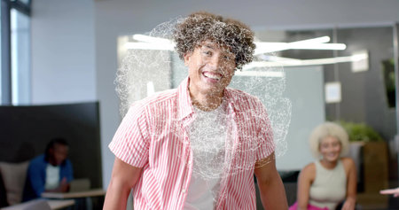 Smiling man wearing pink-striped shirt standing in office lounge, with digital swirl overlay....